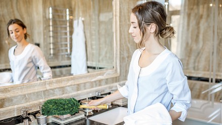 Zimmermädchen reinigt das Badezimmer Zimmermädchen reinigt das Badezimmer