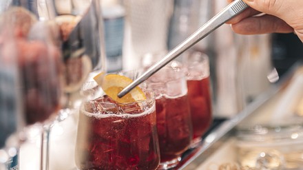 Cocktails Cocktail wir mit einer Zange mit einer Orangenscheibe bestückt
