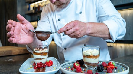 Dessert Dessert von Dolce wird mit einem Sieb und Schokopulver garniert