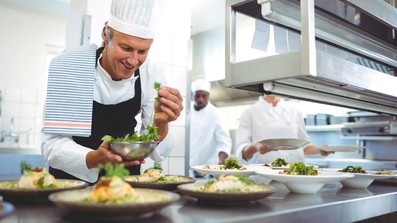 Koch mit Tellern in der Küche