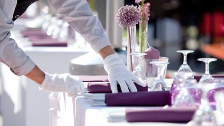 eine Servicekraft deckt einen Tisch