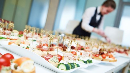 Eine Servicekraft beim Anrichten von kleinen Häppchen