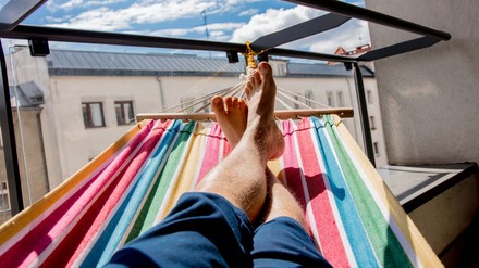 Mann liegt in einer Hängematte auf dem Balkon