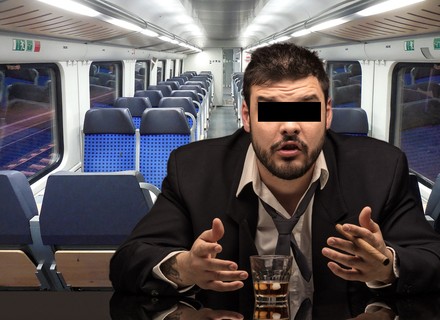Ein Mann mit einem schwarzen Balken über den Augen sitzt mit einem Schnapsglas im Zug