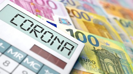 Taschenrechner mit dem Wort Corona im Display, Euro-Geldscheine im Hintergrund