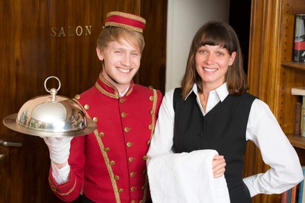 Zwei fröhliche Auszubildende in der Hotellerie bei der Arbeit