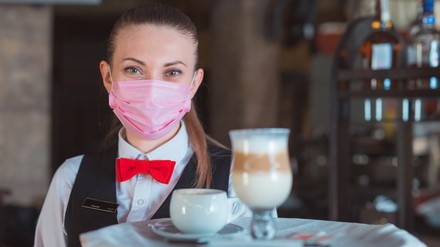 Eine Kellnerin mit Mundschutz
