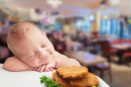 Ein neugeborenes Baby und ein Teller voller Schnitzel