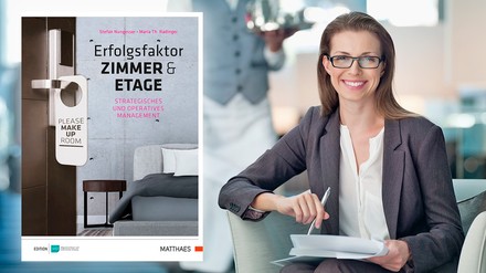 Das Buch „Erfolgsfaktor Zimmer und Etage“, im Hintergrund eine lächelnde Frau in Businesskleidung