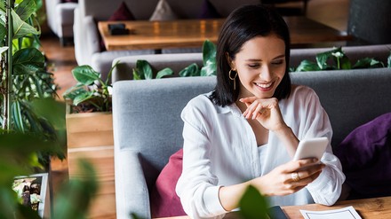 Junge Frau tippt am Smartphone in einem Restaurant