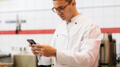 Koch schaut auf sein Handy