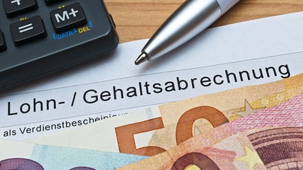 Lohn-/Gehaltsabrechnung, Euro-Gelscheine, ein Taschenrechner und ein Kugelschreiber