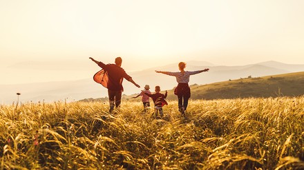 Vater, Mutter und zwei Kinder, die dem Sonnenuntergang entgegen laufen