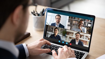 Mann sitzt am Laptop und nimmt an einer Videokonferenz teil