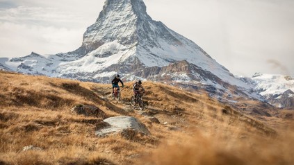 Zwei Mountainbiker auf Tour, im Hintergrund ist das Matterhorn zu erkennen