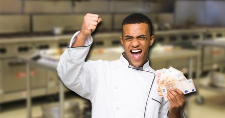 Ein jubelnder Koch mit Geldscheinen in der Hand