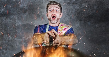 Koch sieht aufgeregt auf seine brennende Pfanne