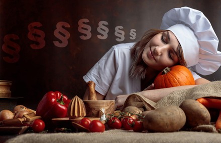 Eine Köchin liegt mit dem Kopf auf dem Tisch und schläft