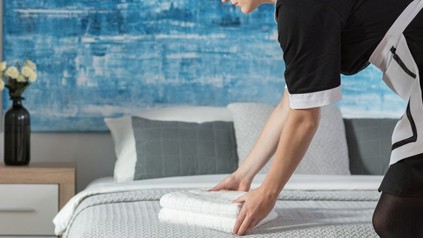 Stubenmädchen legt Handtücher auf dem Gästebett zusammen