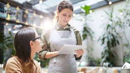 Gastronomin bewirtet Gast im Cafe