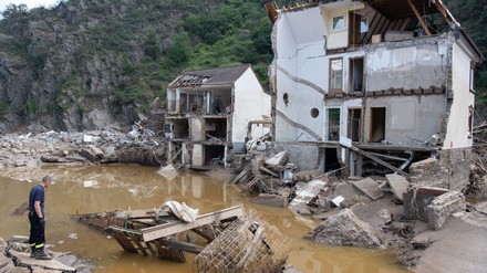 Ein Feuerwehrmann steht im Dorf Mayschoß vor einem völlig zerstörten Haus.