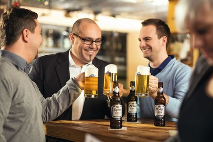 Drei Männer stoßen in Bar mit Bier an