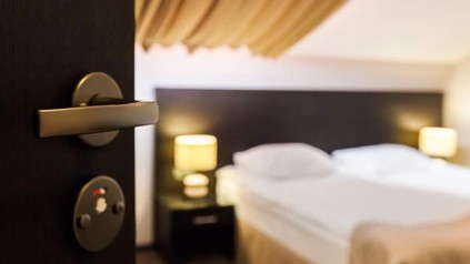 Hotelzimmertür offen, im Hintergrund Hotelbett