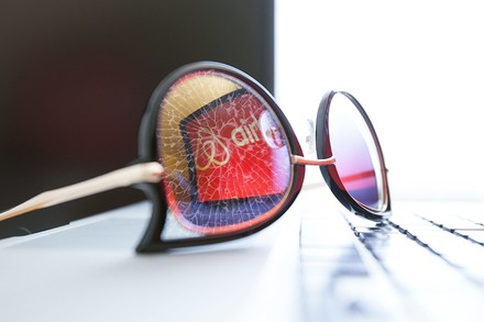 Eine Brille, in der sich das Airbnb-Logo spiegelt