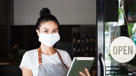 Ein neuer Lockdown ist in Österreich aktuell kein Thema. Andere Maßnahmen sollen helfen, die neue Corona-Welle zu bremsen. (Foto: © Irina – stock.adobe.com)
Junge Dame mit Maske kontrolliert Gäste beim Einlass in das Restaurant