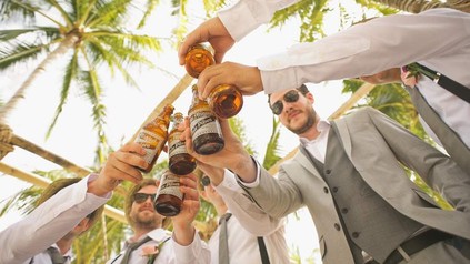 Männer in Anzügen stoßen mit Bier an