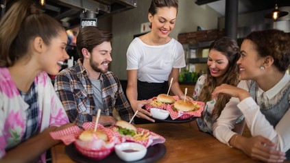 Eine Kellnerin bedient eine Gruppe in einem Burgerlokal