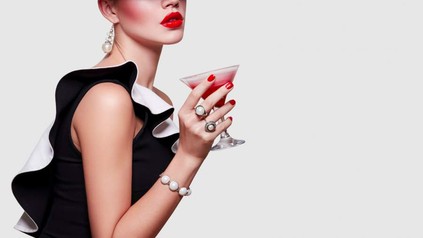 Frau mit Hut hält Cocktail in der Hand