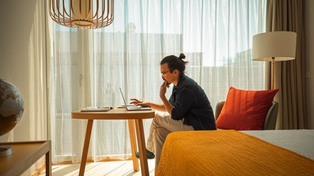 Mann arbeitet in einem Hotelzimmer am Laptop
