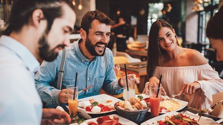 Gruppe Menschen sitzt fröhlich lachend im Restaurant