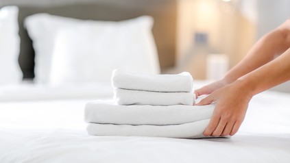 Handtücher werden auf ein Hotelbett gelegt