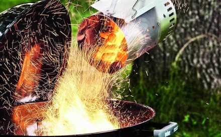 Glühende Kohlen werden in einen Griller geschüttet