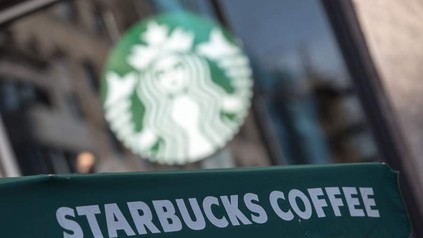 Starbucks Coffee mit Starbucks Logo im Hintergrund