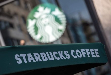 Starbucks Coffee mit Starbucks Logo im Hintergrund