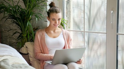 Junge Frau sitzt an ihrem Laptop