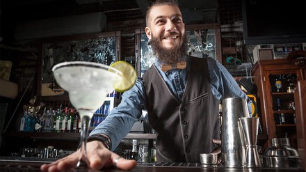 Barkeeper gibt Cocktail an den Gast aus