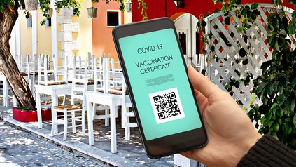 Man hält vor Restaurant Handy mit Impfnachweis