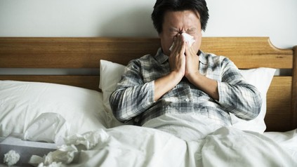 Erkälteter Mann liegt im Bett