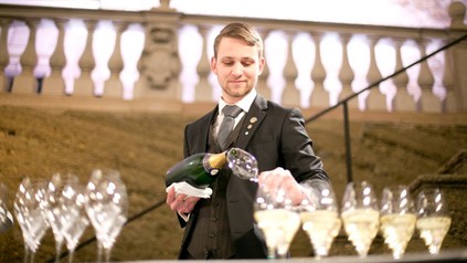 Sommelier schenkt Sektgläser ein