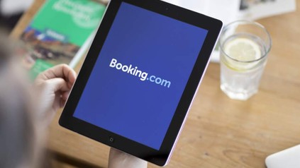 Eine Person hält ein Tablet auf dem die Booking.com App aufgerufen ist