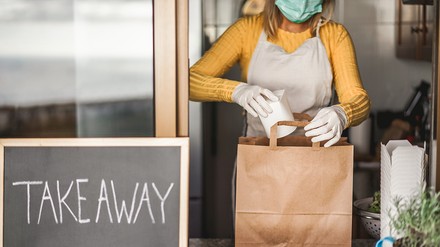 Junge Frau bereitet ein Takeaway-Menü im Restaurant während der Corona-Krise zu