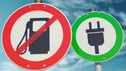 Zwei Straßenschilder: eines zeigt ein durchgestrichenes Tanksymbol, das andere einen grünen Elektrostecker