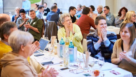 Personen sitzen klatschend an Tischen