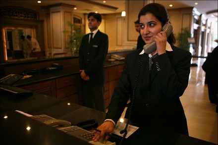 Eine junge Frau telefoniert hinter einer Theke, hinter ihr steht ein Kollege, bereit für den Einsatz