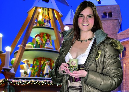 Sarah Schmitt mit einem Glas Glühwein in der Hand vor einem Weihnachtsmarkt
