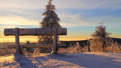 Eine verschneite Bank auf einem Berg mir prächtiger Aussicht